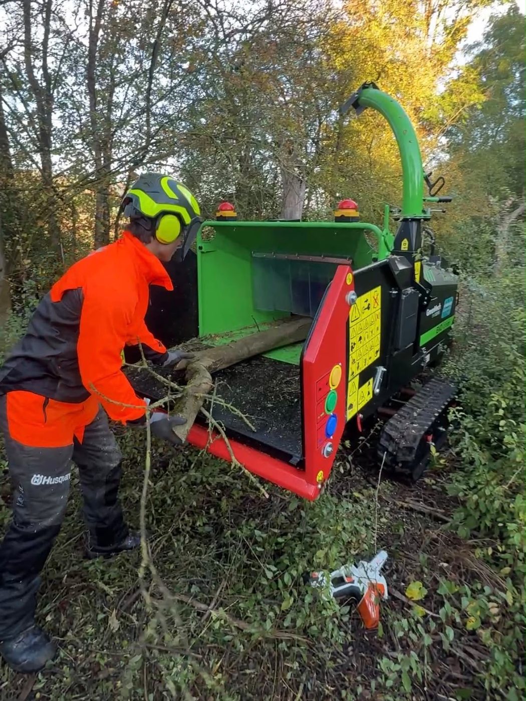 Mitarbeiter mit Helm und Schnittschutz am Häcksler